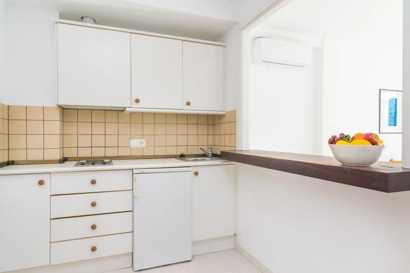 A bright kitchen with white cabinets and a fruit bowl on the counter.