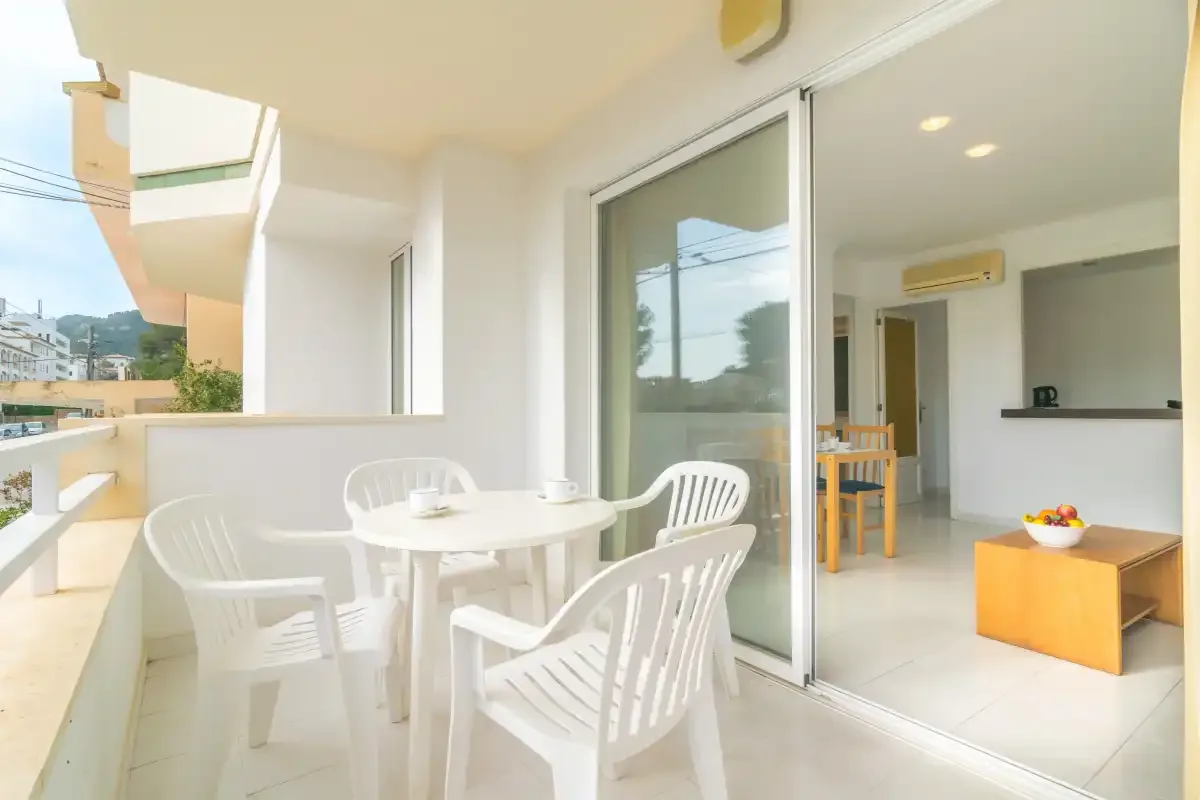 A balcony seating area overlooks a sliding glass door and bright interior.