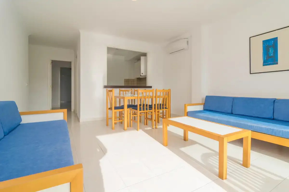 A bright living and dining area with blue seating and a wooden dining table.