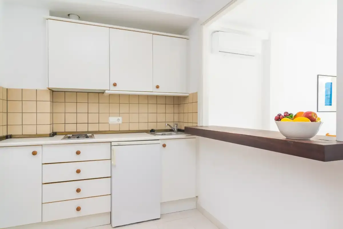 A bright kitchen with white cabinets, a tiled backsplash, and a counter.