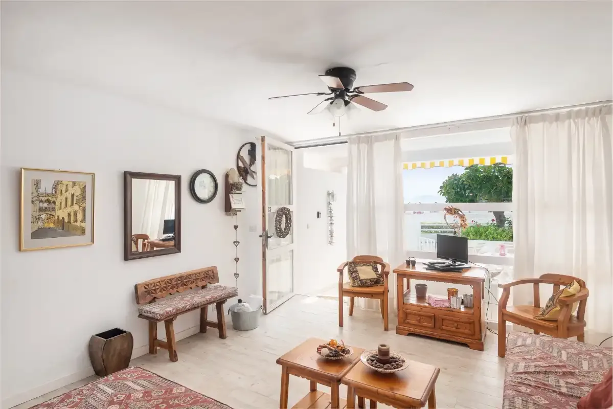 Una sala luminosa con asientos de madera y un televisor junto a la ventana.
