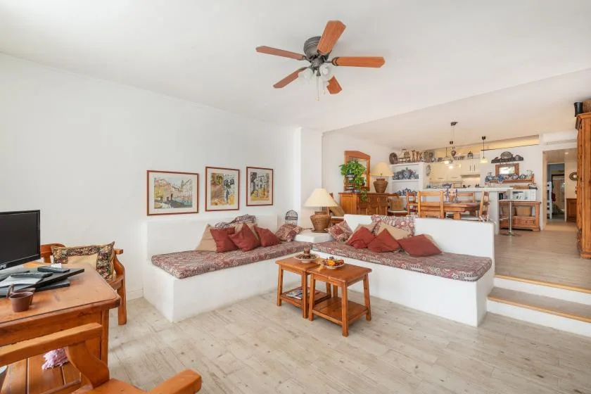 Una sala de estar con asientos integrados y un comedor al fondo.