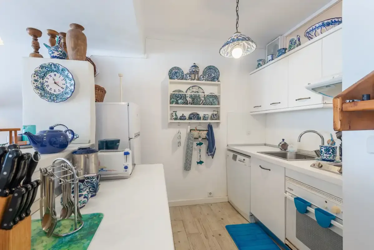 Una cocina luminosa con armarios blancos, una encimera y platos azules y blancos.