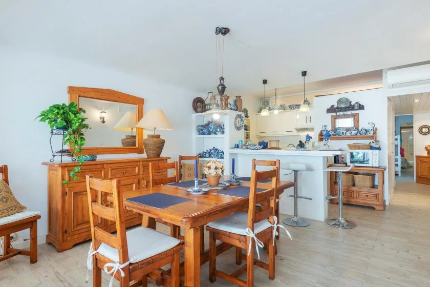 Un comedor con asientos de madera y una barra de cocina al fondo.