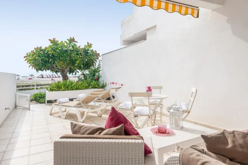 Una terraza al aire libre con asientos, una mesa de comedor y un toldo a rayas.