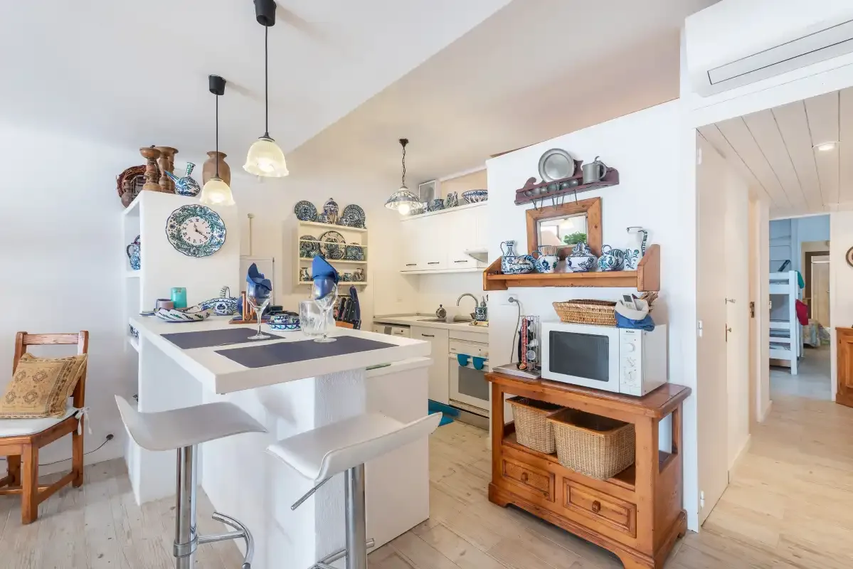 Una cocina luminosa con una isla central, estantes abiertos y un microondas.