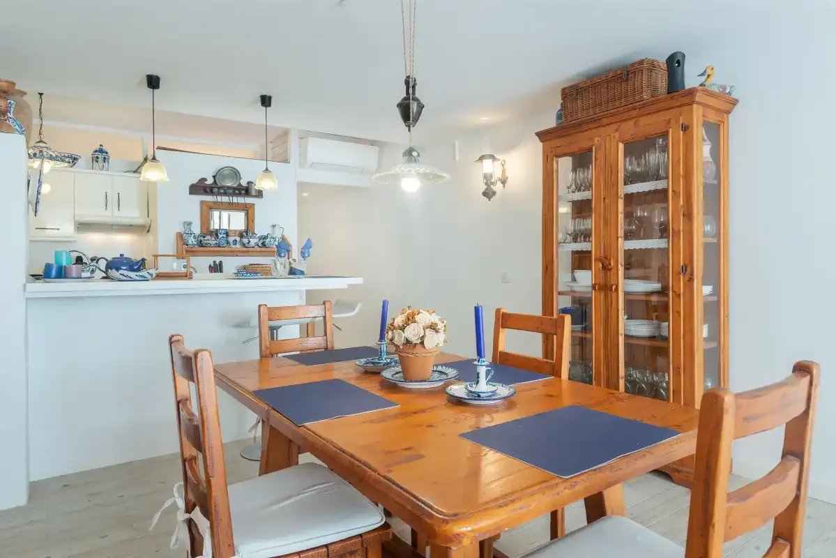 Comedor con una mesa de madera y un armario con puertas de cristal.