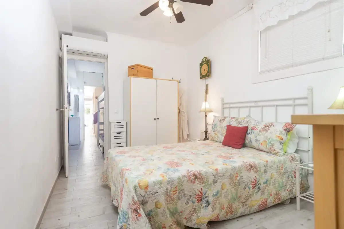 Un dormitorio con una colcha floral, un armario y un ventilador de techo.