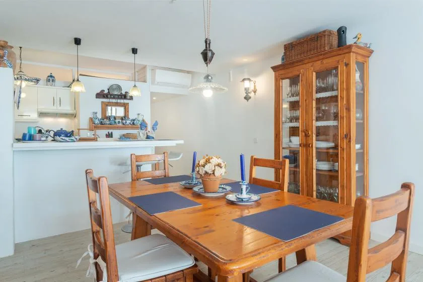 Comedor con una mesa de madera y una cocina abierta al fondo.