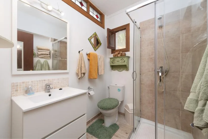 Un baño luminoso con lavabo, inodoro y ducha de vidrio.