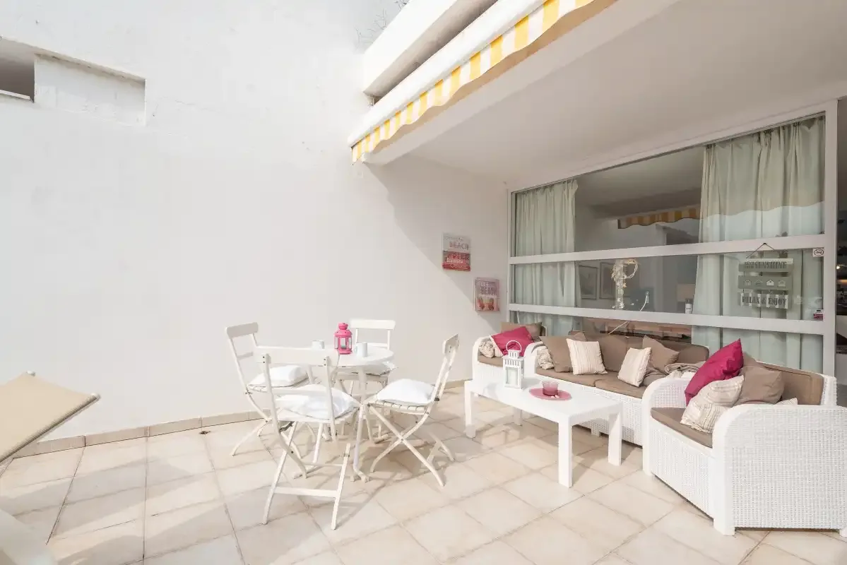 Una luminosa zona de patio con mesa de comedor y asientos acolchados al aire libre.