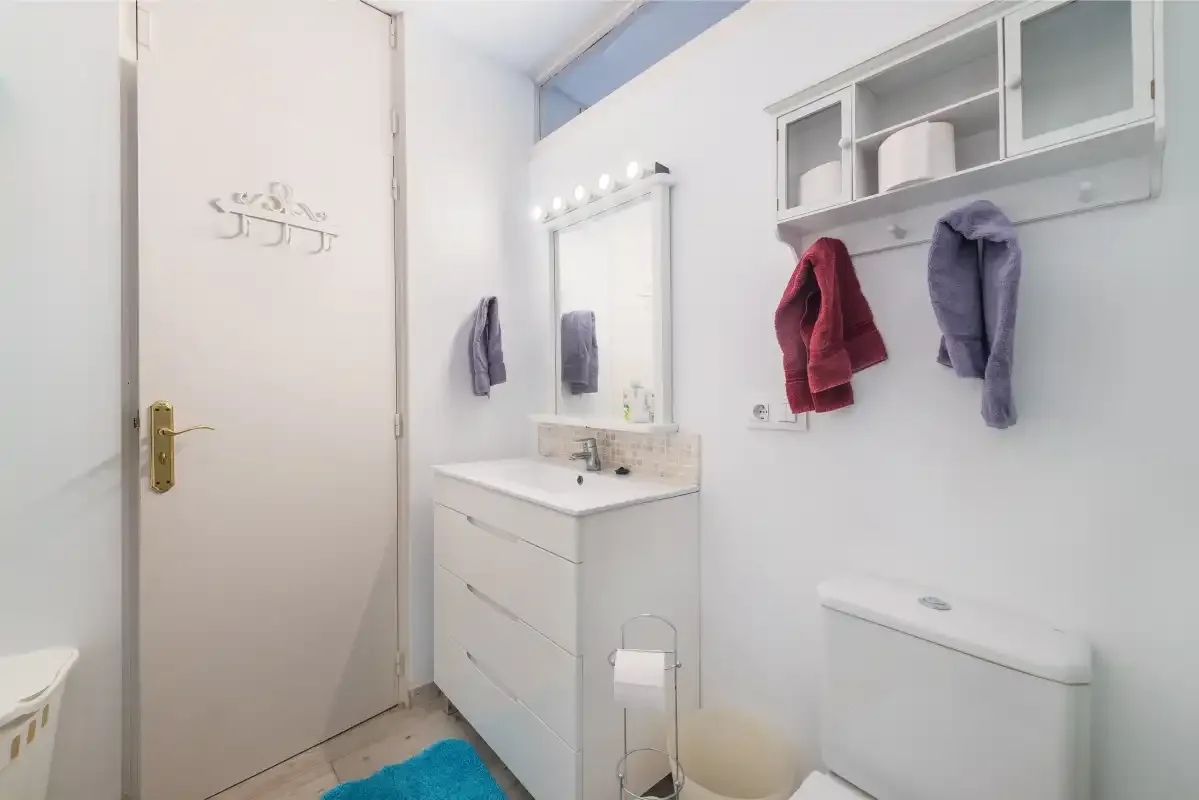 Baño con lavabo, espejo y almacenamiento en la pared.