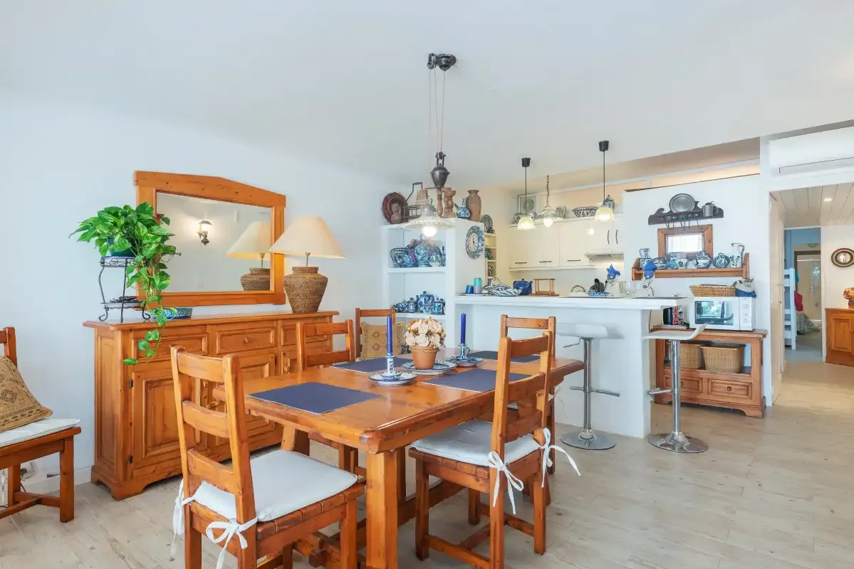 Comedor con asientos de madera y una cocina abierta al fondo.