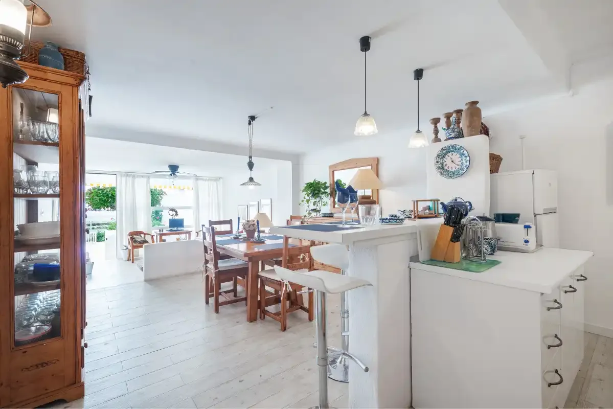 Una cocina luminosa con zona de comedor, encimera y mesa.