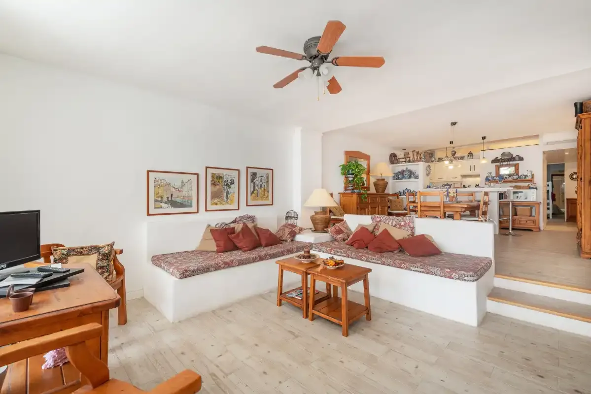 Una sala y comedor abiertos con asientos integrados, una mesa de centro y un ventilador de techo.