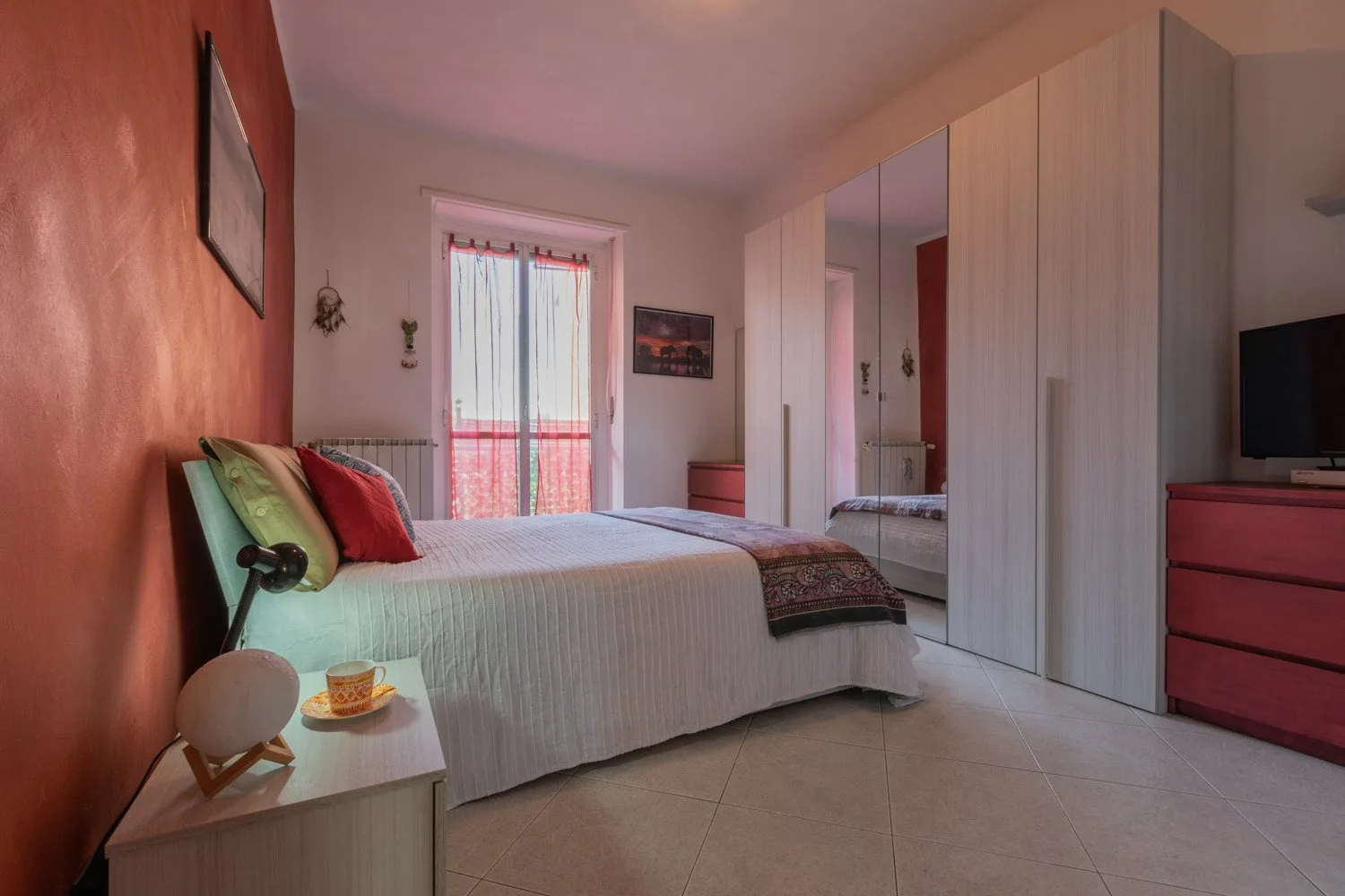 Un dormitorio con una cama junto a una ventana y armarios con espejos.