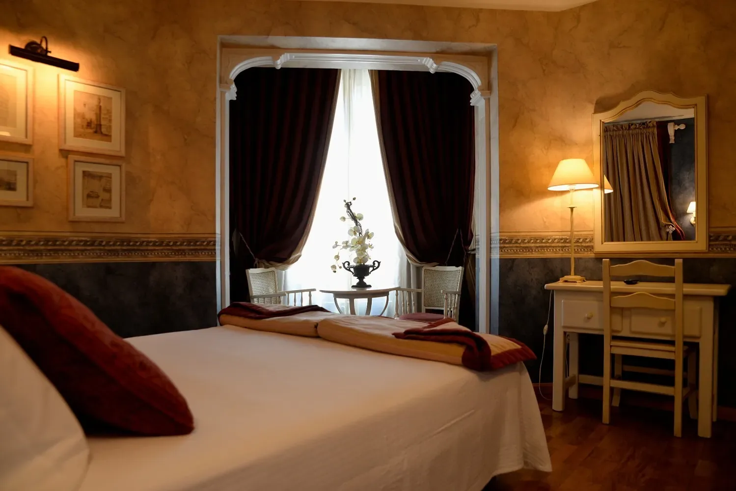 Dormitorio de hotel con una cama blanca y detalles de color burdeos.