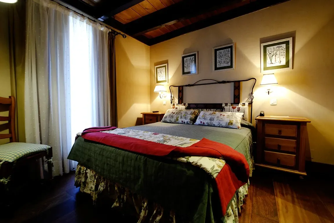 Dormitorio con techo y suelo de madera, cama y cojines decorativos.