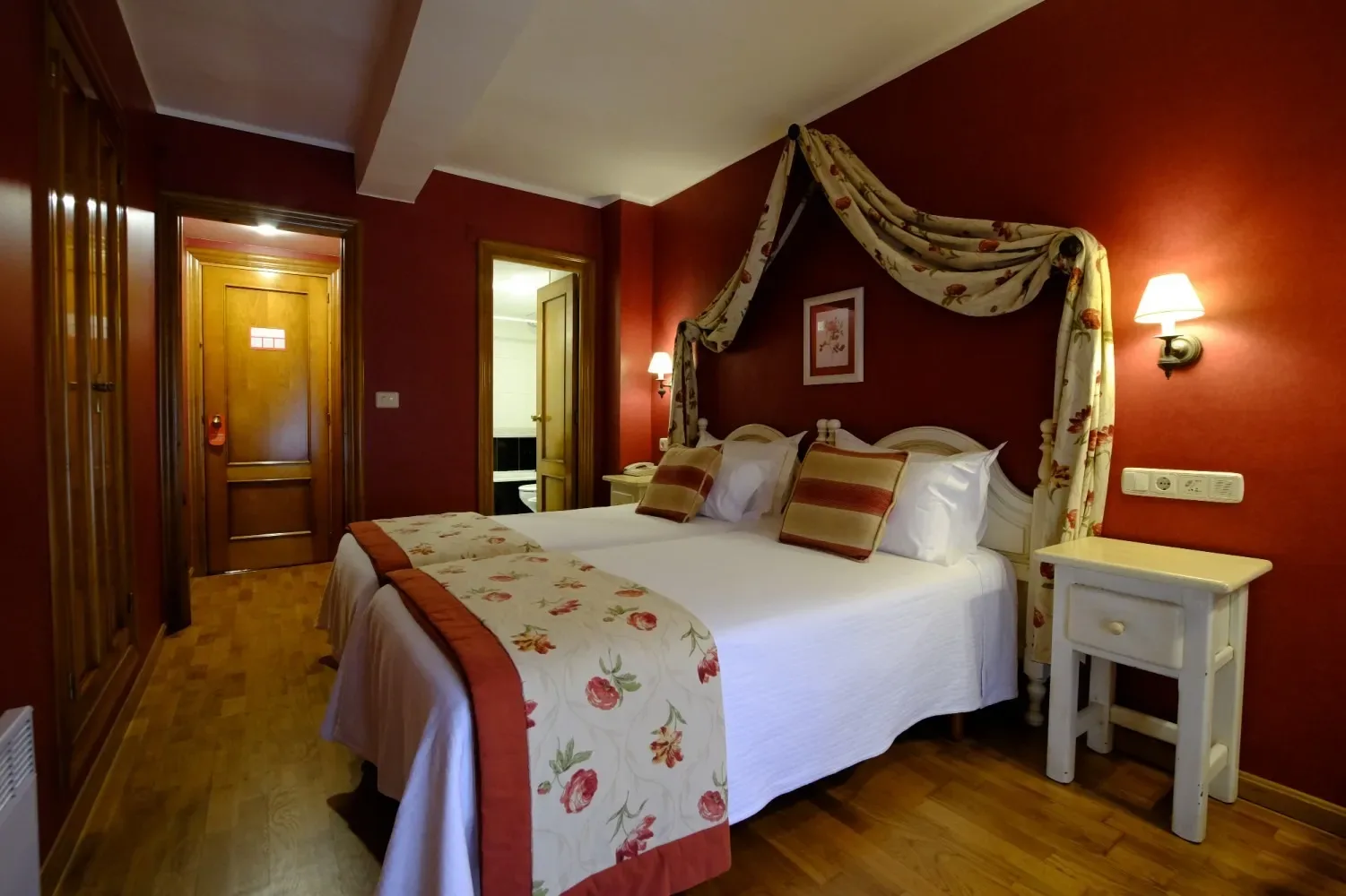 Dormitorio de hotel con paredes rojas y una cama doble.