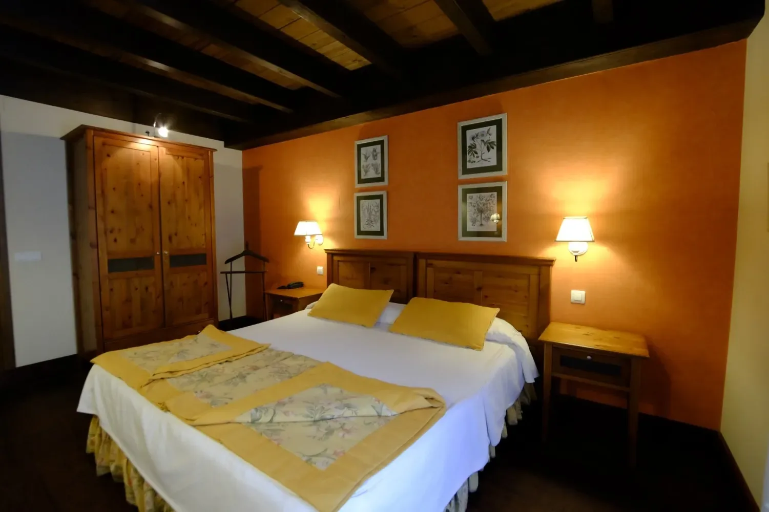Dormitorio con muebles de madera, pared naranja y detalles amarillos en la cama.