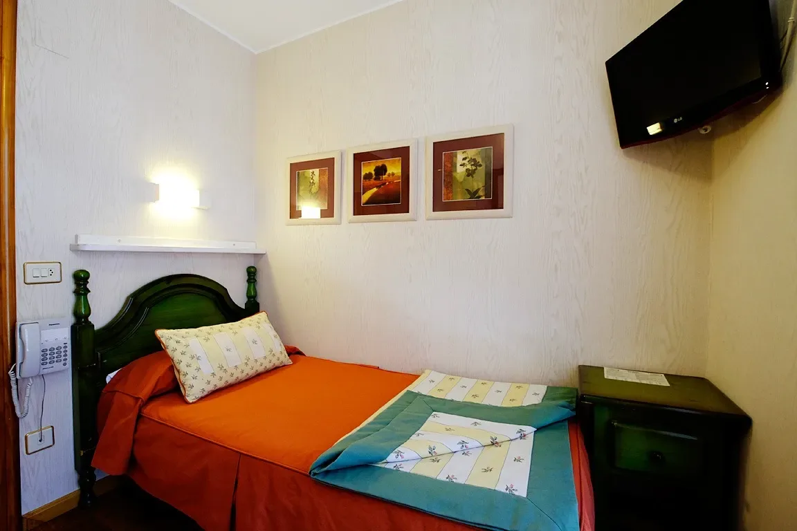 Habitación pequeña de hotel con una cama individual y televisor.