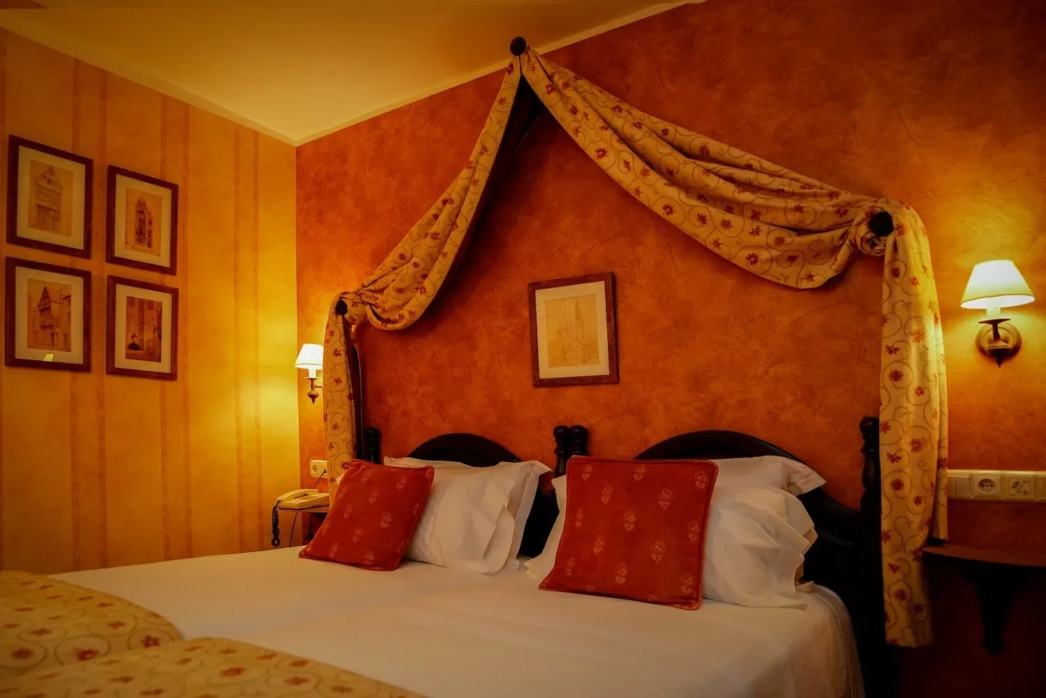 Dormitorio de hotel de ambiente cálido con una cama con dosel y paredes naranjas.
