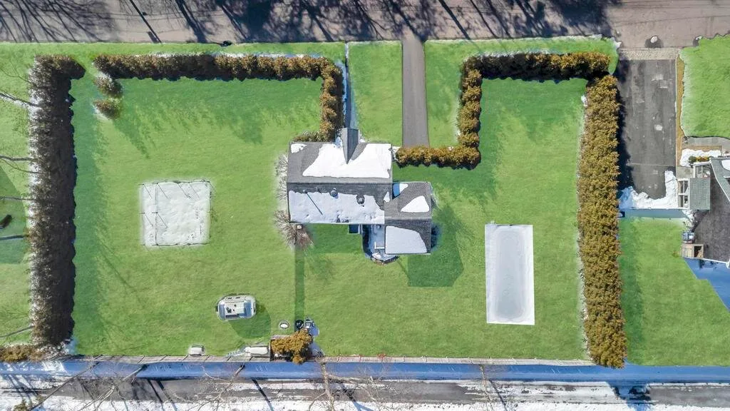 Aerial view of a house surrounded by lawns and hedges.