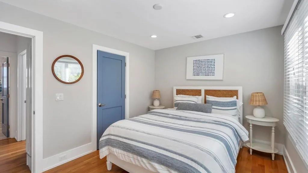 A bedroom with a bed dressed in striped bedding and a blue door.