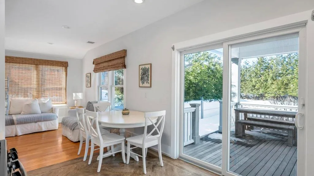 A dining area beside a sliding glass door opens onto a deck.