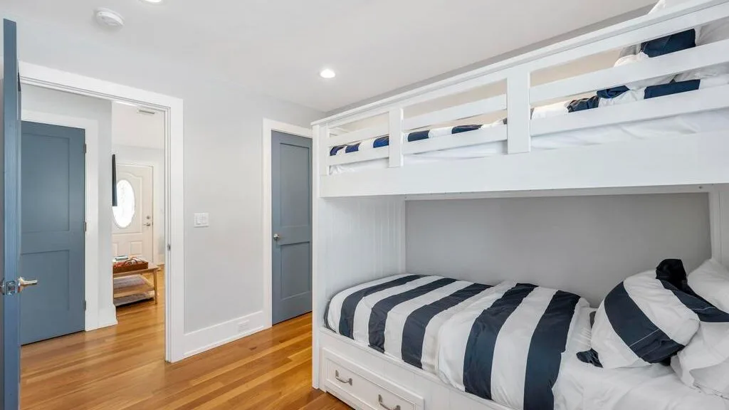 A bedroom with a built-in bunk bed and striped bedding.