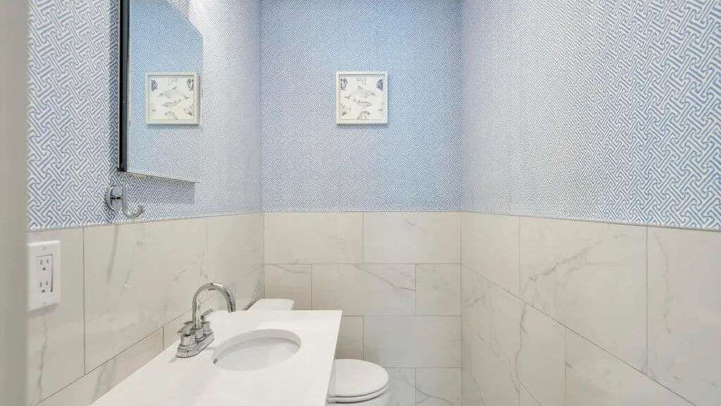 A tiled bathroom with a sink, mirror, and toilet.