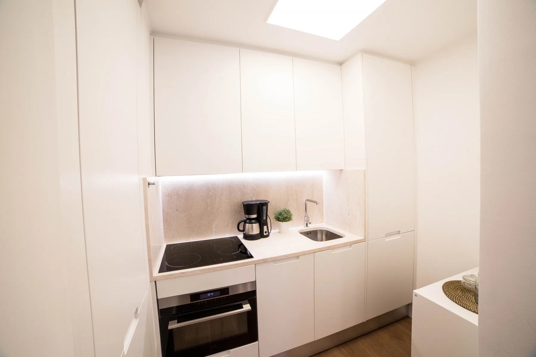 Una cocina compacta con armarios blancos, una placa de cocina y una encimera.