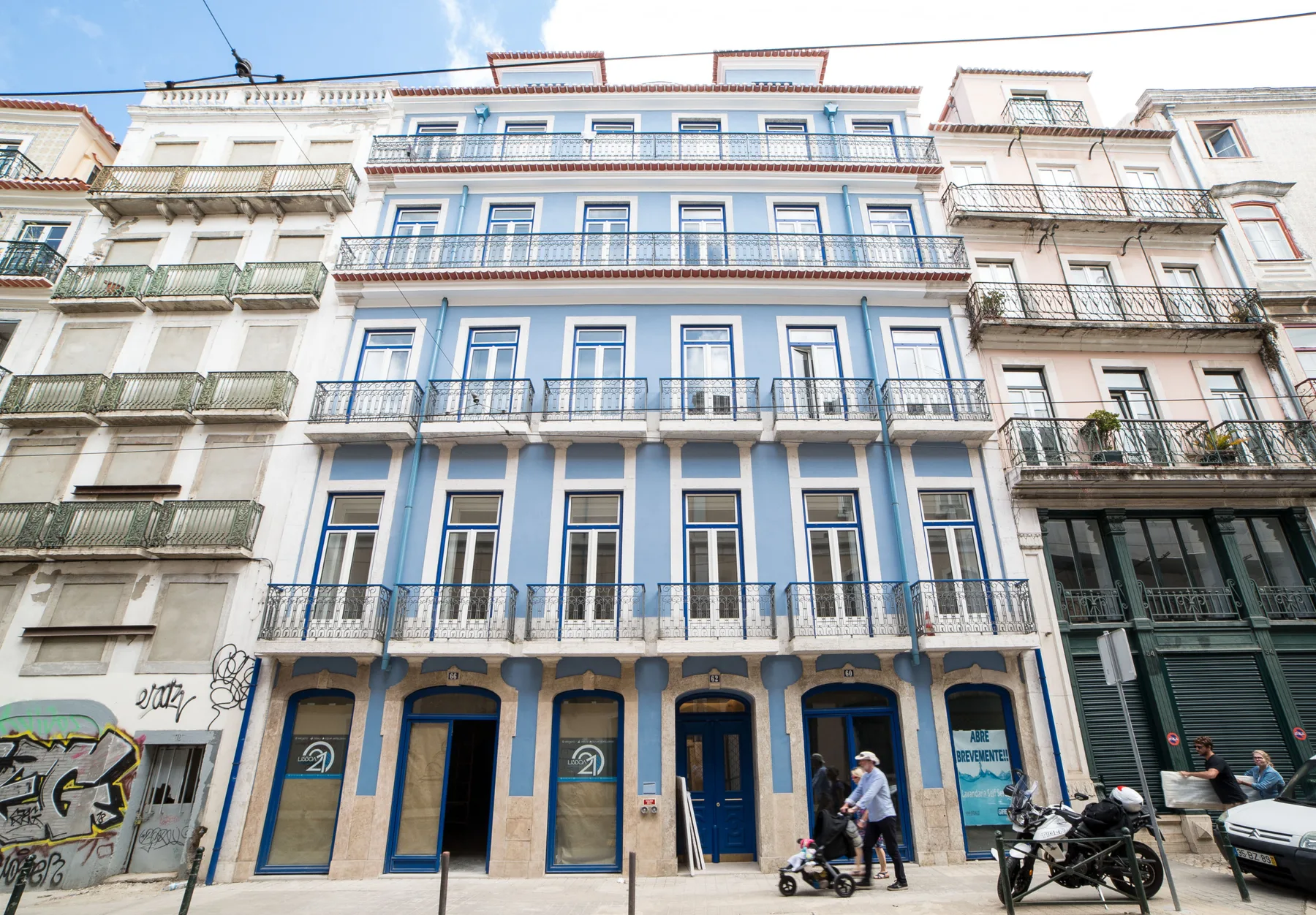 Vista de la calle de un edificio de varias plantas con ventanas azules y balcones.