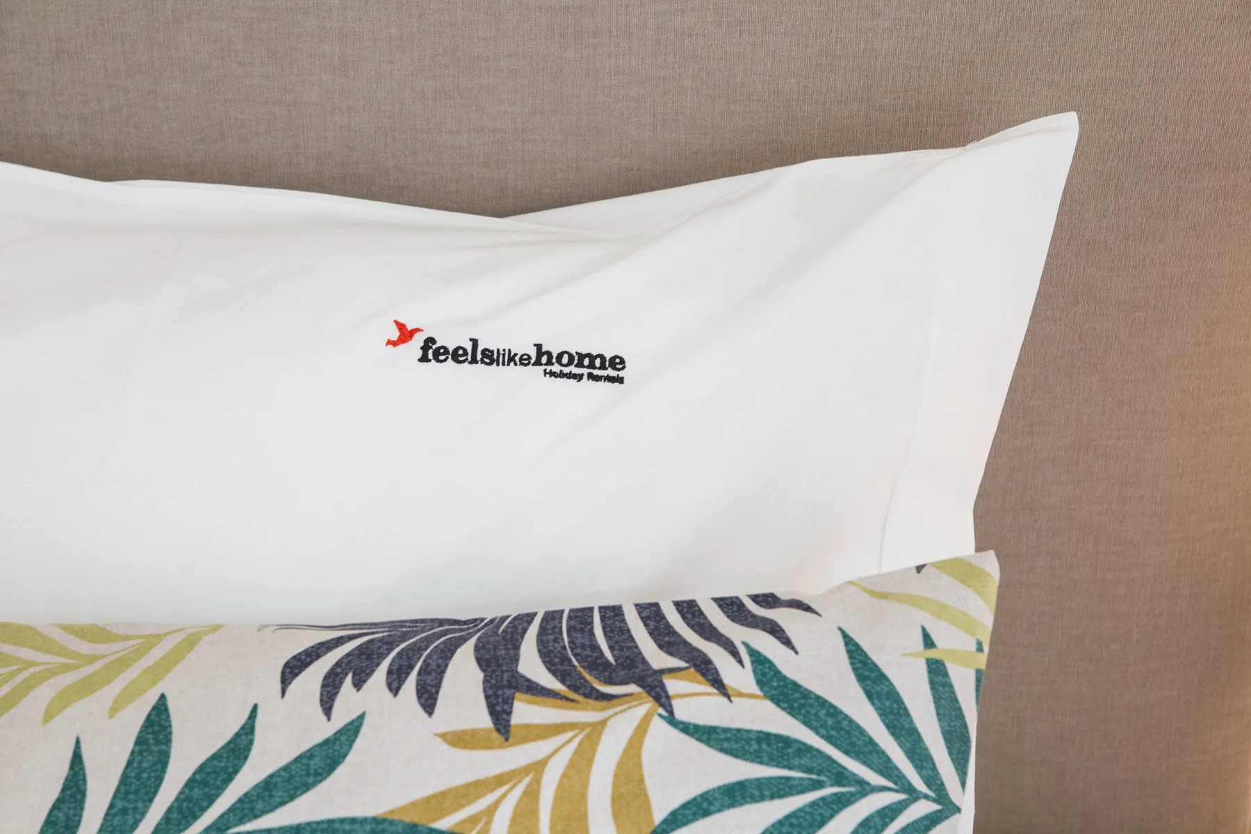 Primer plano de ropa de cama blanca con una almohada estampada de colores.