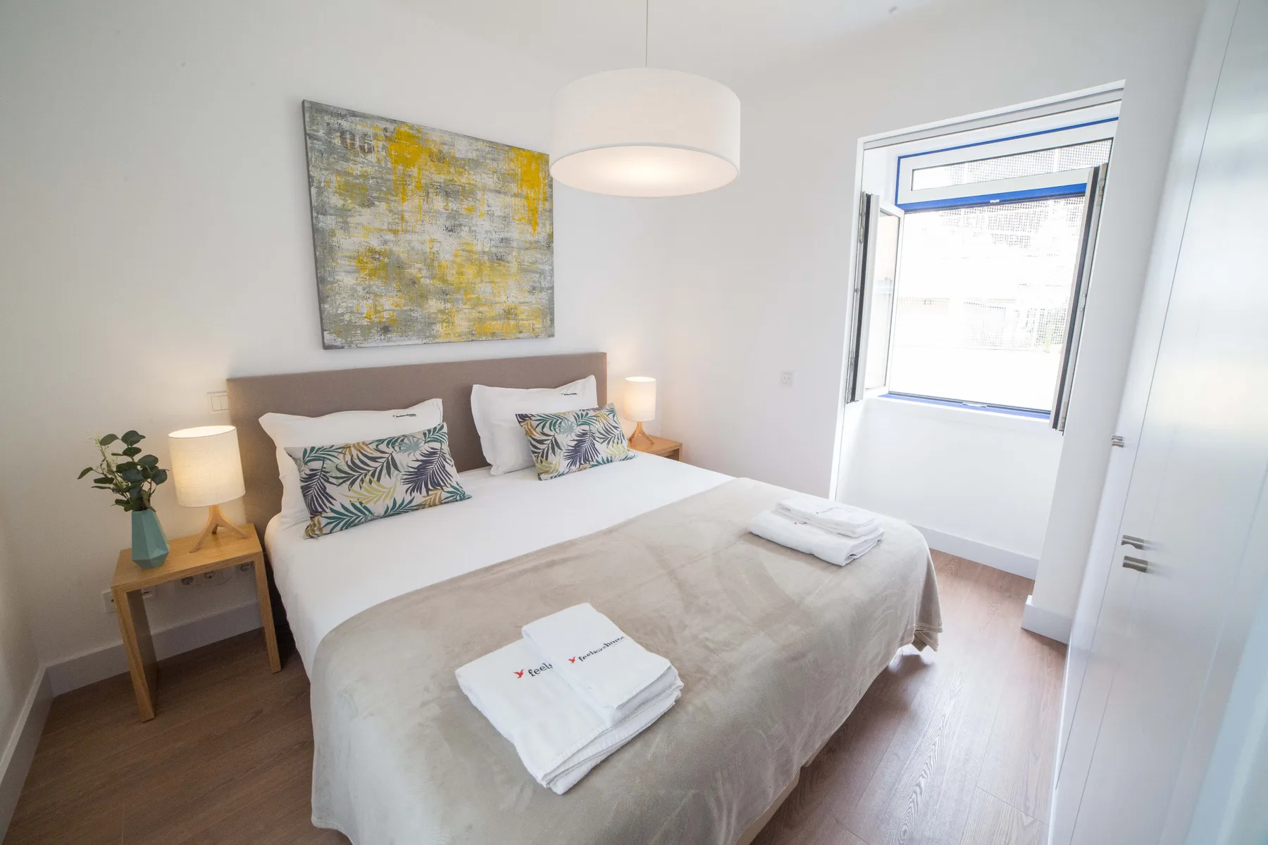 Un dormitorio luminoso con una cama bien hecha y una ventana grande.