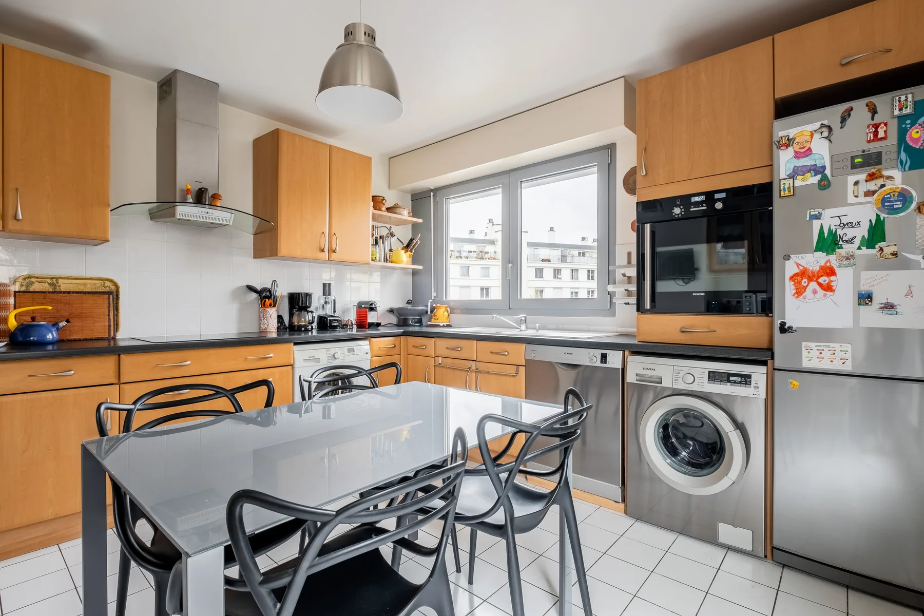 A modern kitchen with a dining table and large windows.
