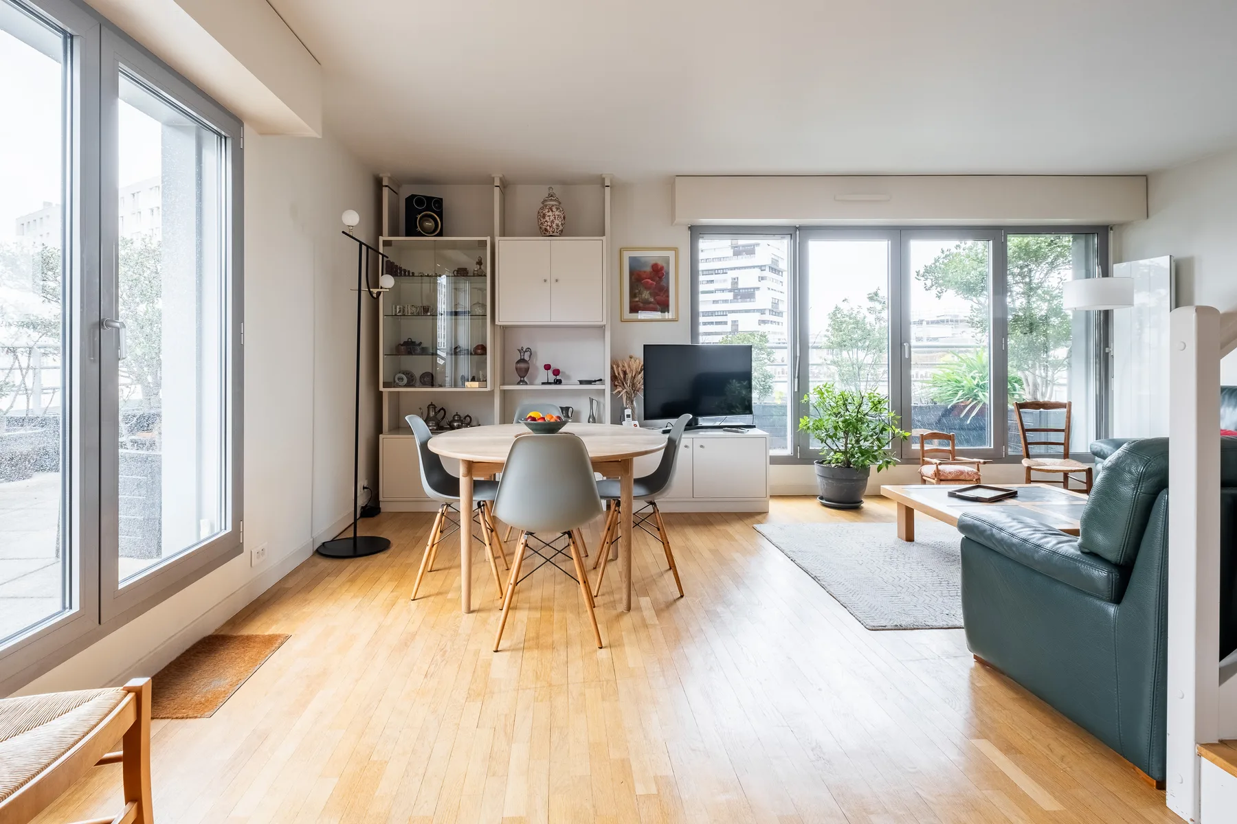 A bright living and dining area with large windows and a table.