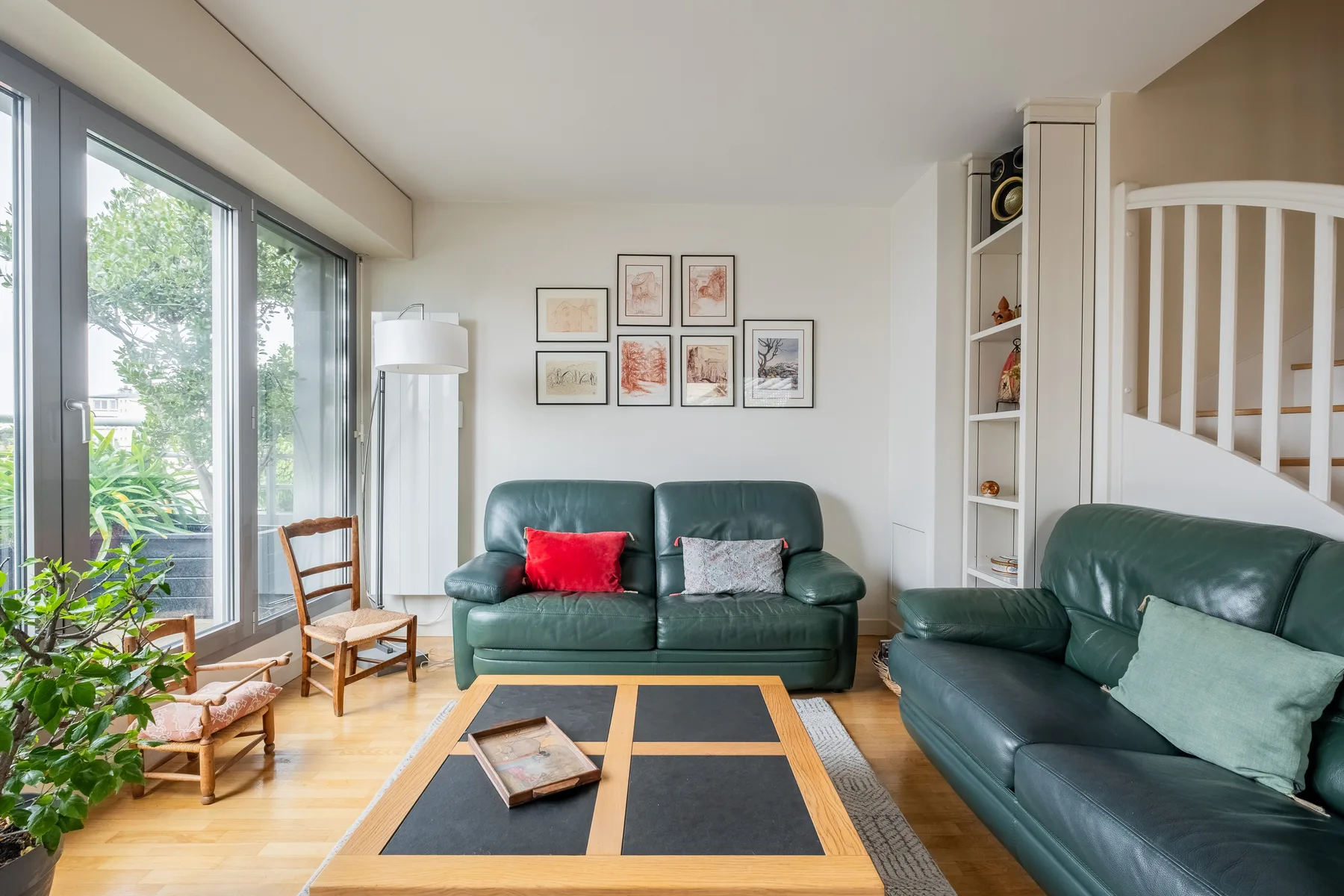 A living room with green seating, a coffee table, and large windows.
