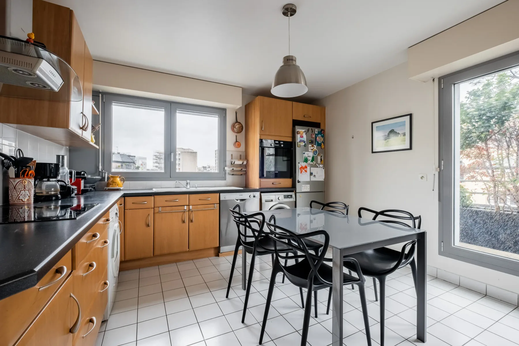 A bright kitchen with wood cabinets, a dining table, and large windows.