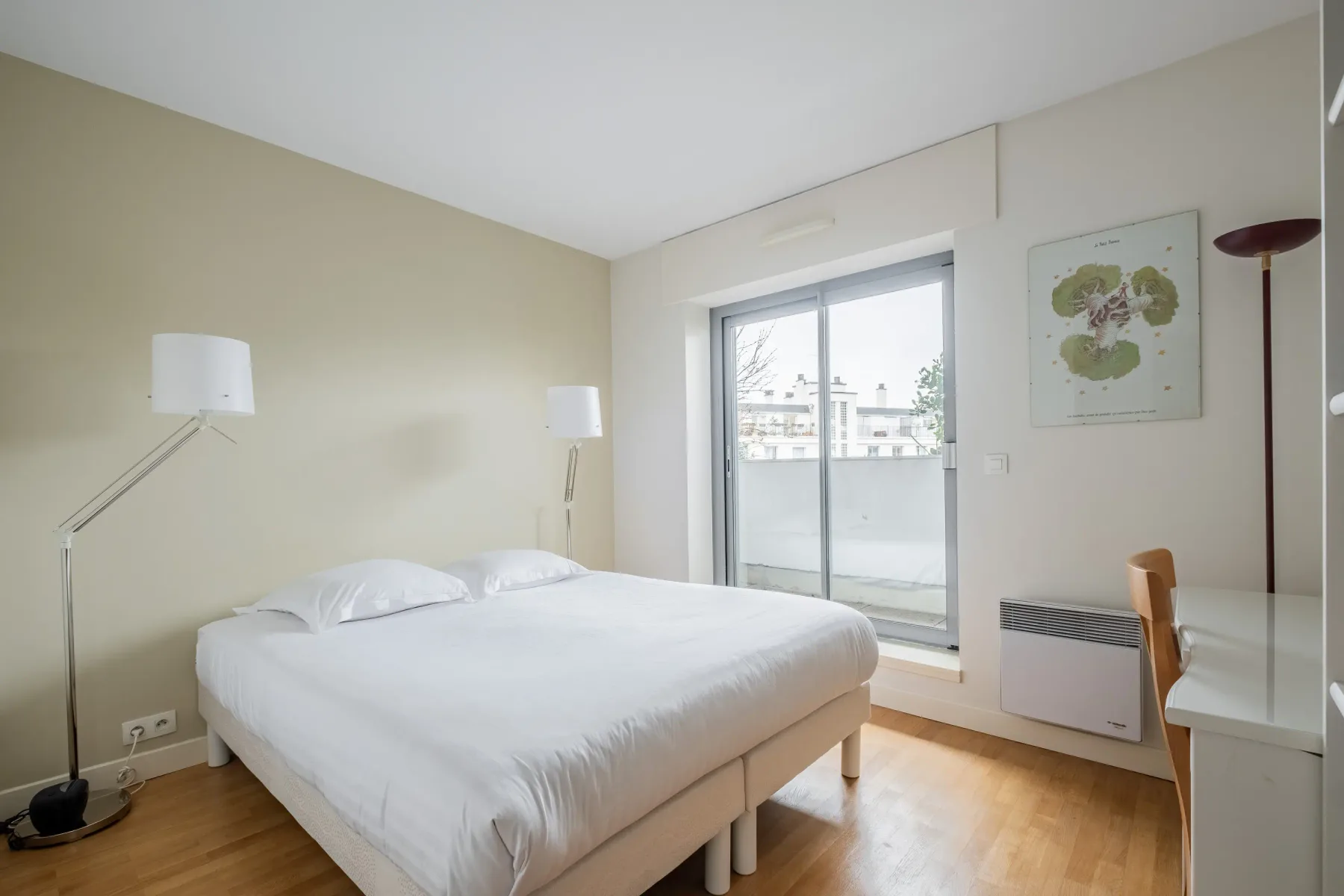 A bright bedroom with a neatly made bed beside a large window.