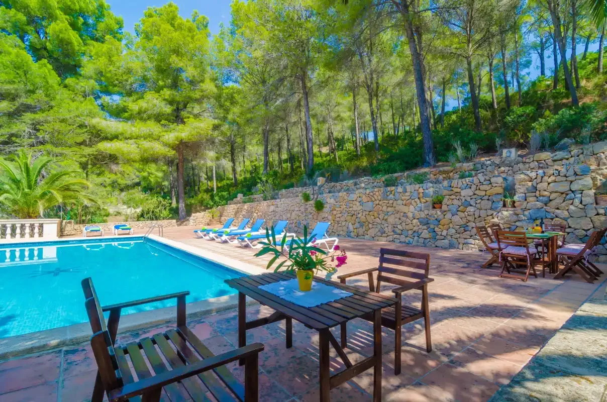 Una piscina al aire libre junto a asientos de patio y un muro de contención de piedra.