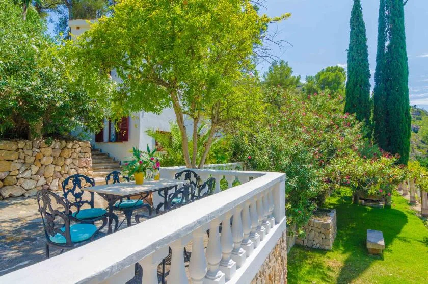 Una terraza al aire libre con asientos da a un jardín verde.
