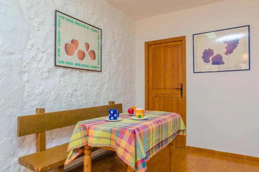 Un comedor con una mesa de madera cubierta con un mantel de cuadros colorido.