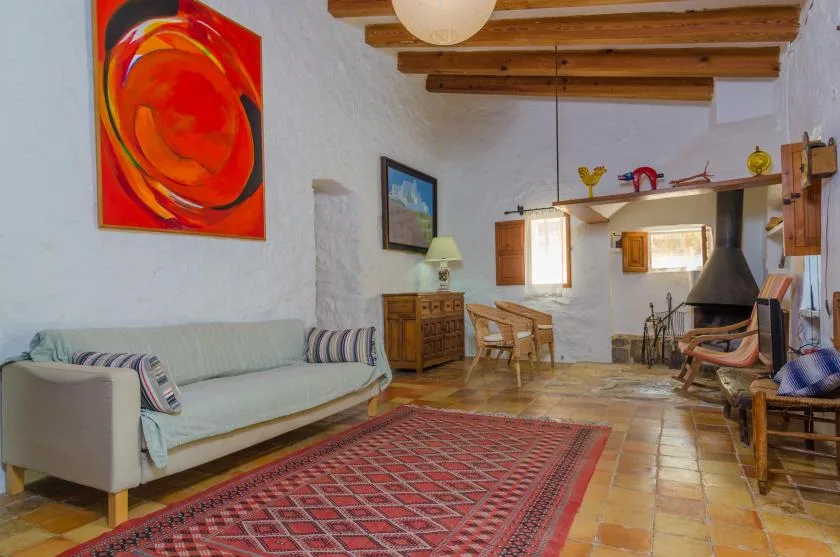 Una sala rústica con asientos, una alfombra estampada y vigas de madera a la vista.