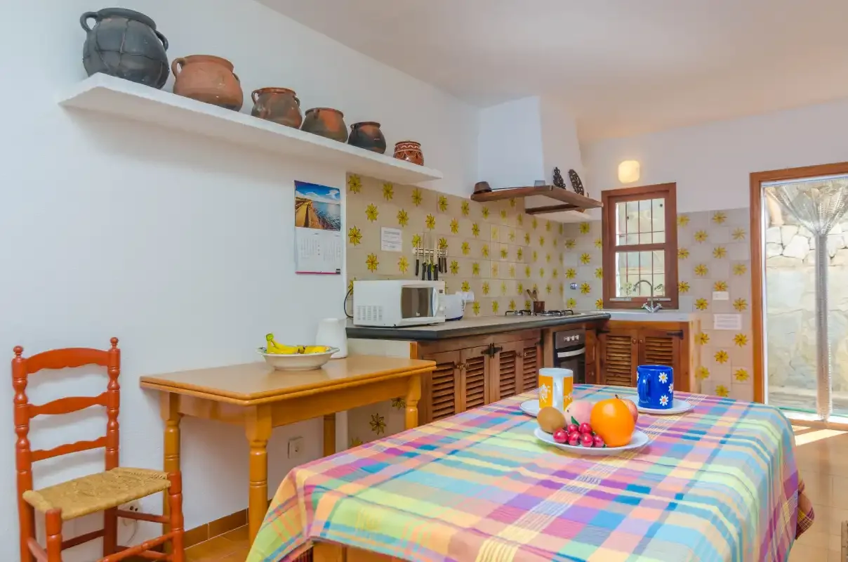 Una cocina y comedor con un mantel de cuadros colorido y armarios de madera.