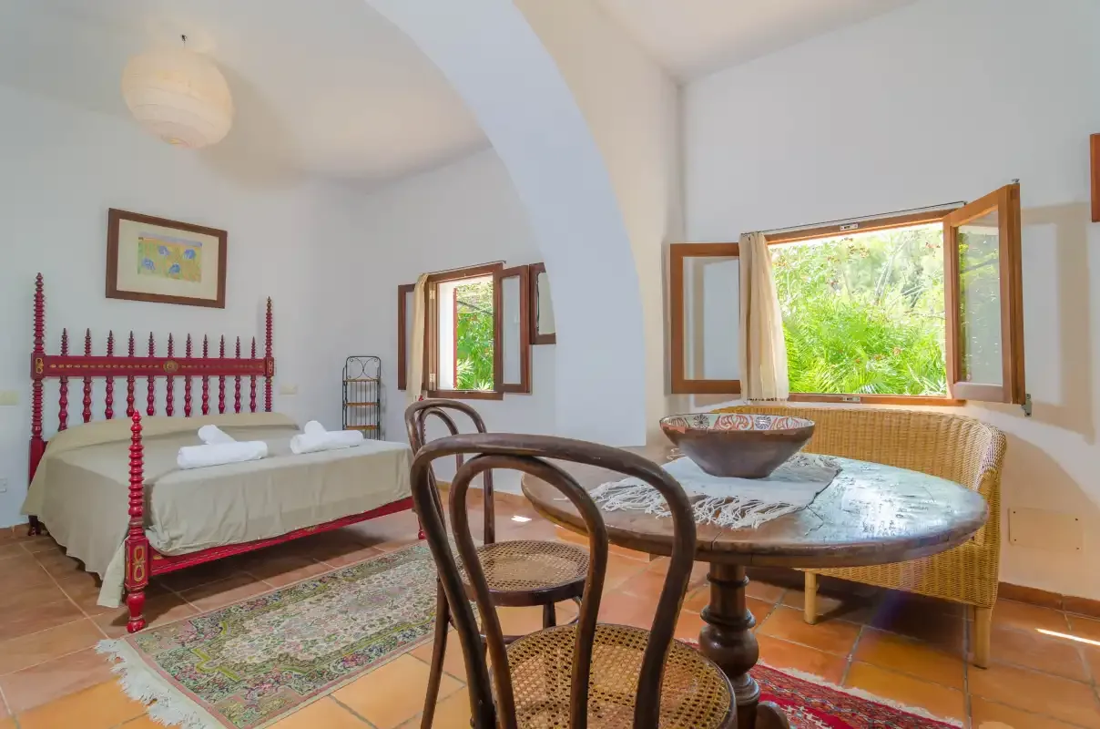Un dormitorio con una mesa de comedor y ventanas abiertas.