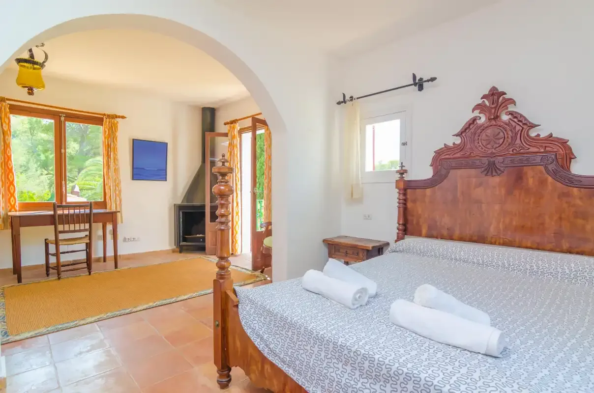 Un dormitorio con una cama de madera ornamentada y una zona de estar contigua.