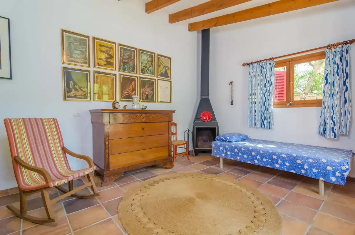 Un dormitorio con una estufa de leña, una cómoda y una cama cubierta de azul.