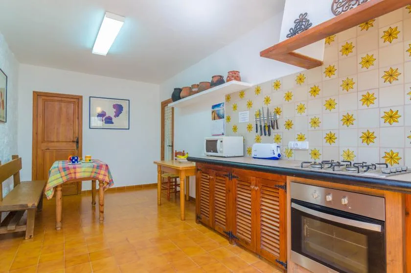 Una cocina con mesa de comedor, gabinetes de madera y azulejos decorados.