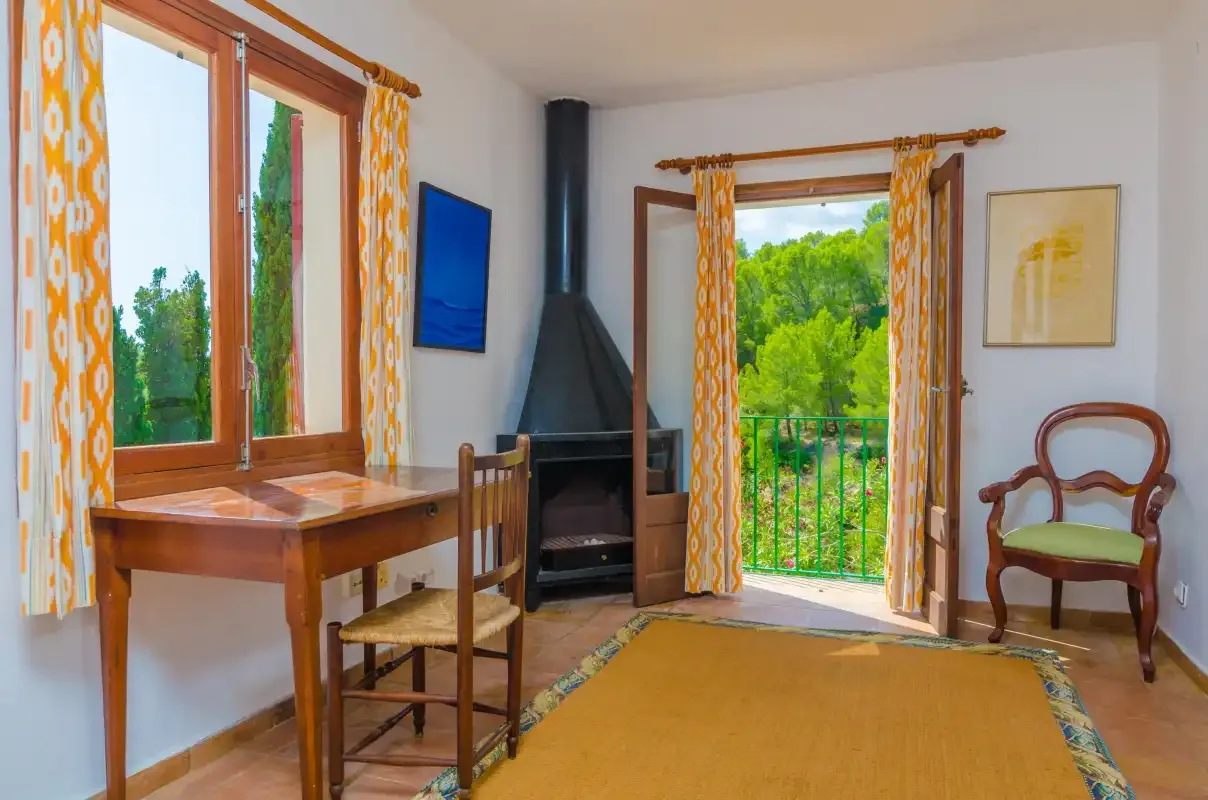 Una sala luminosa con una mesa de madera y un balcón con vistas a la vegetación.